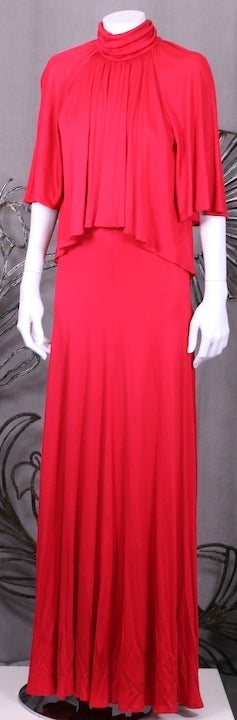 1970's Scott Barrie tomato red rayon matte jersey gown with the look of separates. The cropped flutter top is attached at the neck and dips in the back. Ruched gathered mock turtle. Back zip entry.
Size 8 vintage, Size 4-6 modern  60