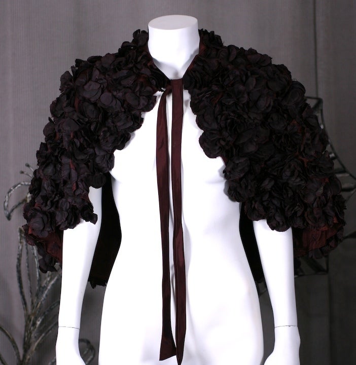 1930s cape decorated with hundreds of floral fabric blooms. Originally this capelet was a vibrant red color. Over the years the unstable dyes in the rayon have faded the flowers to an amazing goth shade of deep aubergine similar to dried rose
