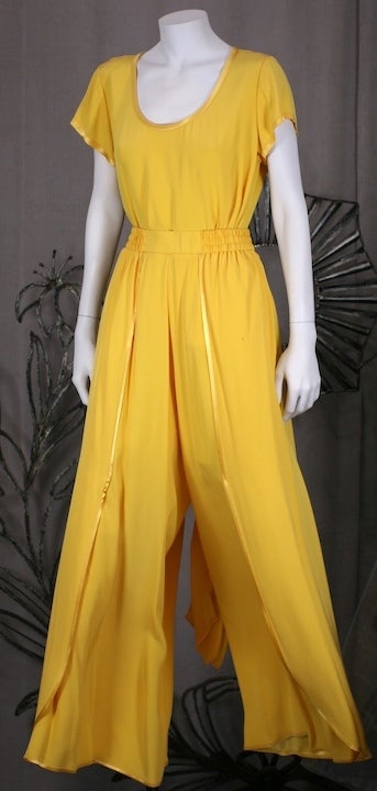 2 piece chrome yellow ensemble by Yves Saint Laurent in his favorite satin backed rayon crepe. A simple cap sleeved T shirt is paired with his favorite split leg pant which reveals the satin face when the wearer moves. It is designed to resemble a