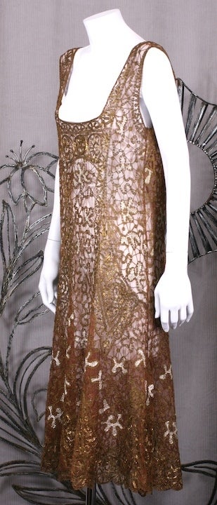 Extraordinary French handmade dress from the 1920's. Built on a silk tulle base, panels of coppery tinsel and gold lame thread are hand overembroidered and crocheted into swirl motifs. Inserts of gold lame are caught in the embroideries to create