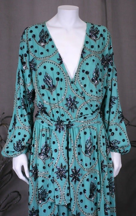 Turquoise silk chiffon maxi wrap dress with the ease of a dressing gown. Easy wrap dress styling ties inside and hooks across the elasticized waist. A self beaded belt completes the ensemble. Completely lined in turquoise as well. Iridescent