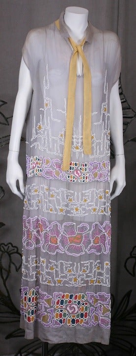 1920s cotton muslin day dress in pale grey with pale yellow attached tie with transitional Art Nouveau/Deco Japonesque floral embroideries and beadwork.  The skirt is heavily embroidered in bands of bright floral motifs in purples, milk and primary