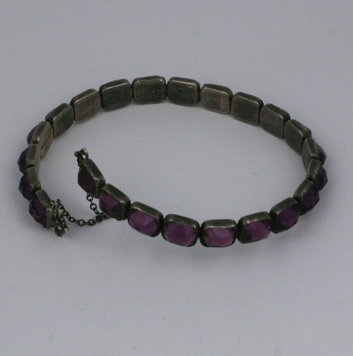 Unusual amythest paste crossover bracelet in sterling from the 1920's. High dome faceted stones in flexible band settings with safety chain. 7.5