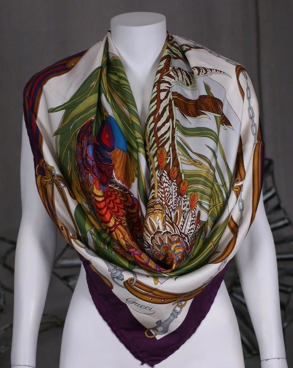 Oversized silk twill scarf by Gucci with vibrantly colored graphic of a pheasant in its natural habitat. Signature Gucci belted detailing around border.  35