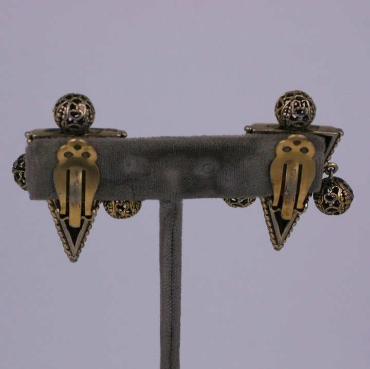 Les boucles d'oreilles de Schiaparelli en métal doré vieilli de style néo-Victorien, avec des décorations étrusques et des perles en métal filigrane, imitent les bijoux archéologiques du XIXe siècle.
 .
Les bijoux fantaisie de Schiaparelli des