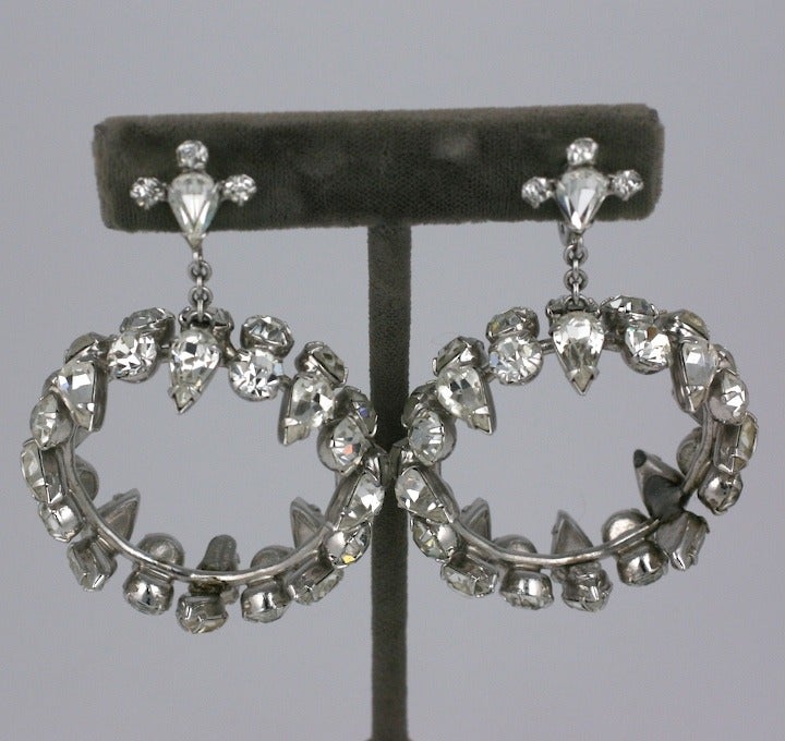 Rhinestone hoop drop earrings from the 1950s with clip back fittings. The hoops are set with pear shaped and round stones in a dimensional pattern that creates a hard edged look. Very unusual configuration. 2.75