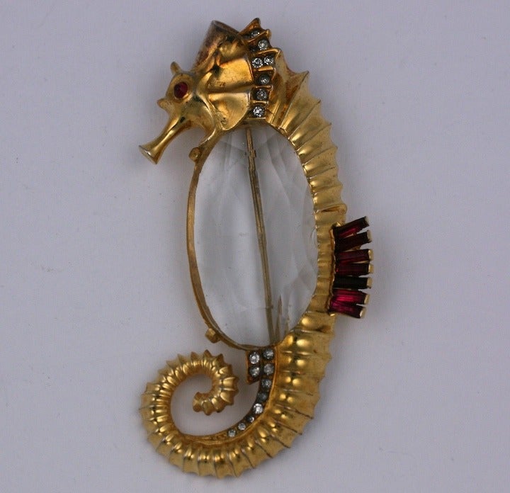 Seahorse brooch from the late 1930s of gilt yellow and pink  metal, crystal pave and ruby baguettes with a large faceted cut crystal oval  belly. Unsigned. Excellent condition. 1930s USA.
3.5