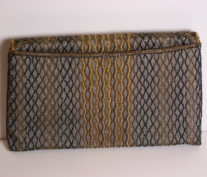 Unusual clutch of silvery taupe brocade with applied bronze and enamel metal filigrees with copper, taupe and gold seed beads in a wave pattern. There are also tiny gold chain decorations embroidered into the pattern as well which travel to the back