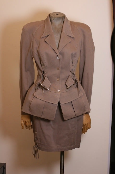 Thierry Mugler's taupe cotton twill safari suit complete with pinched corseted waist, self belt, lacings and heavily backed peplum. 
Size 38.  France 1990's. Very Good condition.
Jacket length: 26
