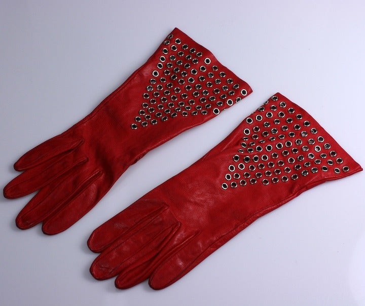 Iconic and rare early Azzedine Alaia red gauntlets studded with grommets in a V formation. Retailed at Bergdorf Goodman. NY. Small Size. One grommet off on lower right wrist, not noticeble when worn.
Very Good Condition. France 1980s.