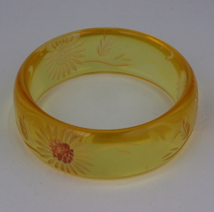 Carved apple juice Bakelite bangle with floral designs. One flower has a highlighted patinaed center. 1930s USA. 
Excellent condition.