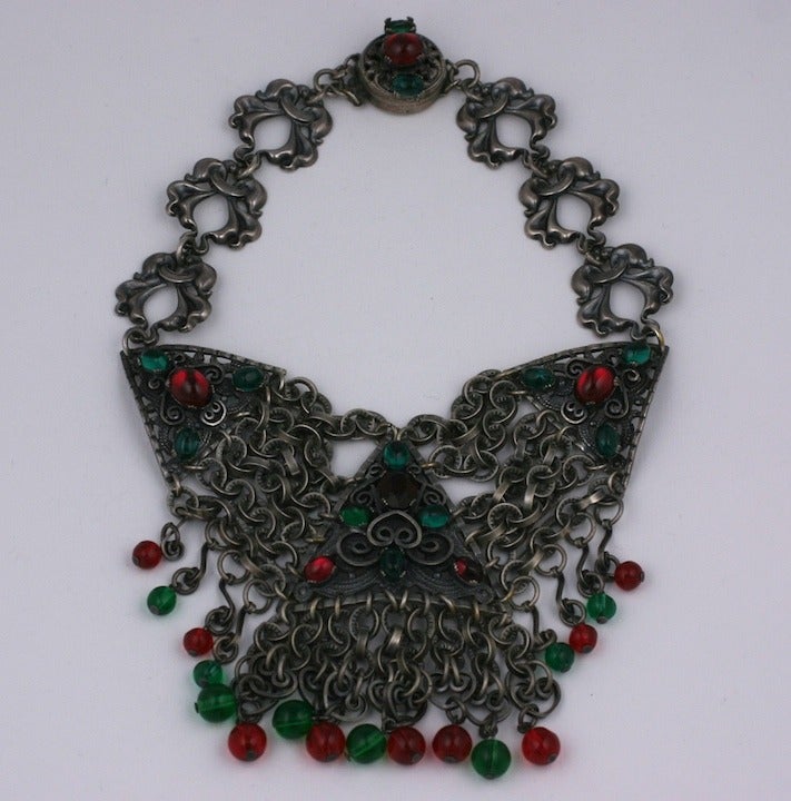 In the 1930's costume jewelry houses created facsimiles of jewelry styles from all over the world. This American necklace was inspired by Austro-Hungarian jewelry but is scaled in a larger more ornate, evening fashion. 
Deep silver metal is