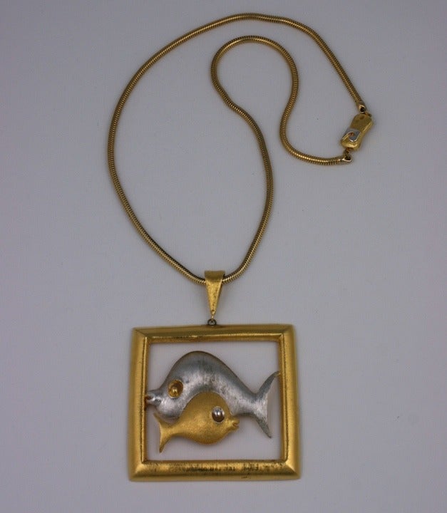 Pierre Cardin pendant necklace of gold and silvered metal with large and small fish swimming in opposite directions. Set in burnished metal, Signed on the clasp and pendant back. 20