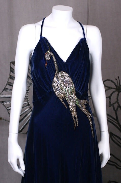 Bias cut royal blue velvet 1930's gown with hand embroidered rose monte bird  design. Hundreds of hand set rhinestones are hand applied in varying shades to form the coloration for the bird of Paradise. 
Velvet is gathered at waist front and skirt
