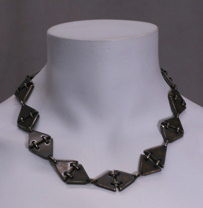 Modernistisches Collier aus abgedunkeltem Messing, das aus dreieckigen Gliedern besteht, die ineinander verschlungene Diamantstationen bilden.
.75