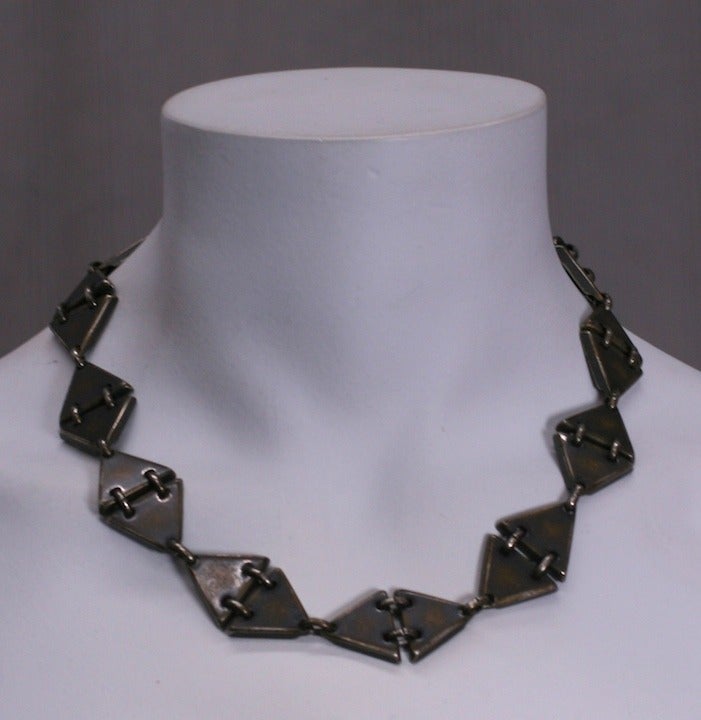 Collana modernista in ottone scurito e consumato, composta da maglie a forma di triangolo che formano stazioni articolate di diamanti.
Larghezza 0,75