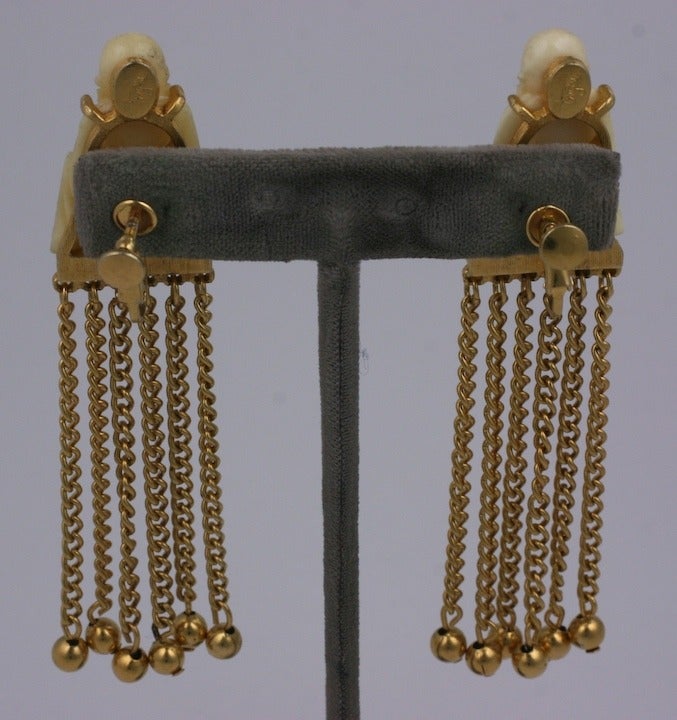 Long chain embellished earrings by Pauline Trigere. Faux ivory buddhas sit on the ear with clip back fittings. 1960's USA. Excellent condition.  3.5