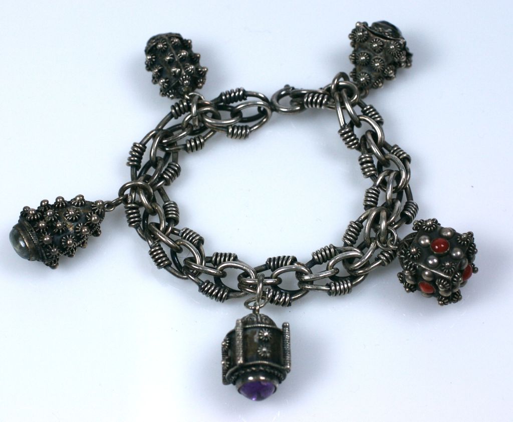Chunky charm bracelet of 800 silver with stone set charms. Amythest, coral, labradorite and turquoise cabochons are used on the filigreed charms.<br />
These were very popular in the 1950s. Attractive ornate twisted wire chain link. on brac.<br