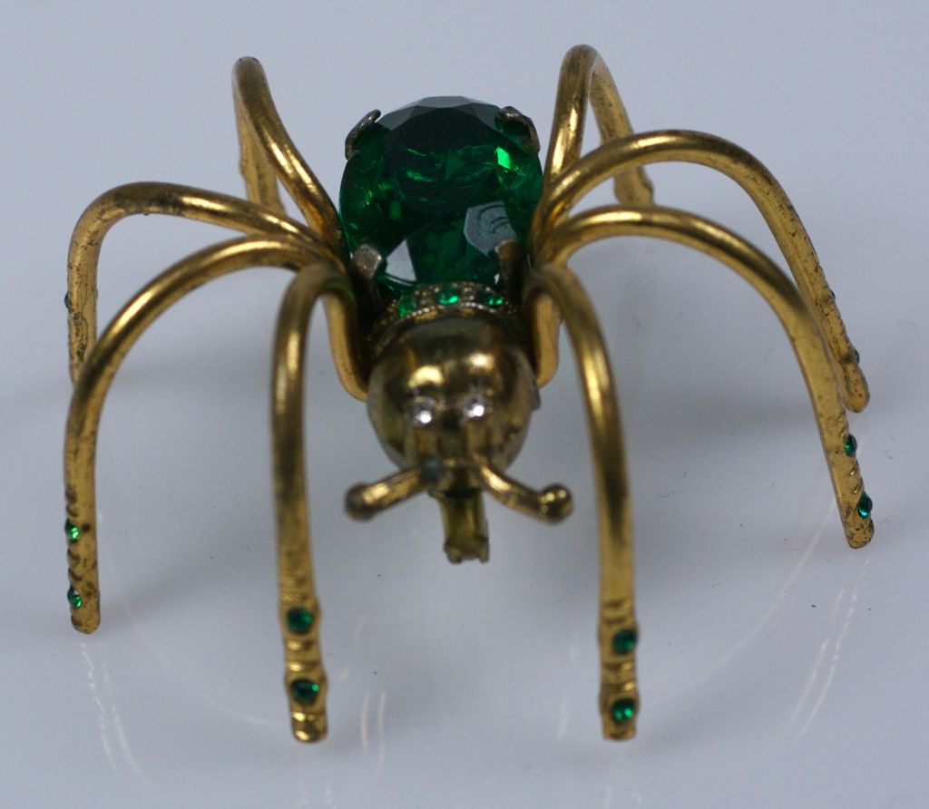 Charming spider brooch with large faux emerald as body. Small little green stones are studded on his legs and back as well. This brooch is very dimensional and works well on a sweater or heavier gauge material as he looks like hes actually climbing