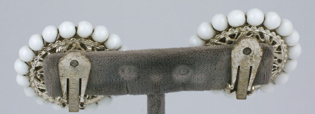 Les boucles d'oreilles d'été de Miriam Haskell sont constituées de perles d'eau douce et de perles en pate de verre blanc laiteux dans un motif de cercles concentriques.<br />
Montés sur métal doré argenté avec dos à pince.<br />
Excellent état<br