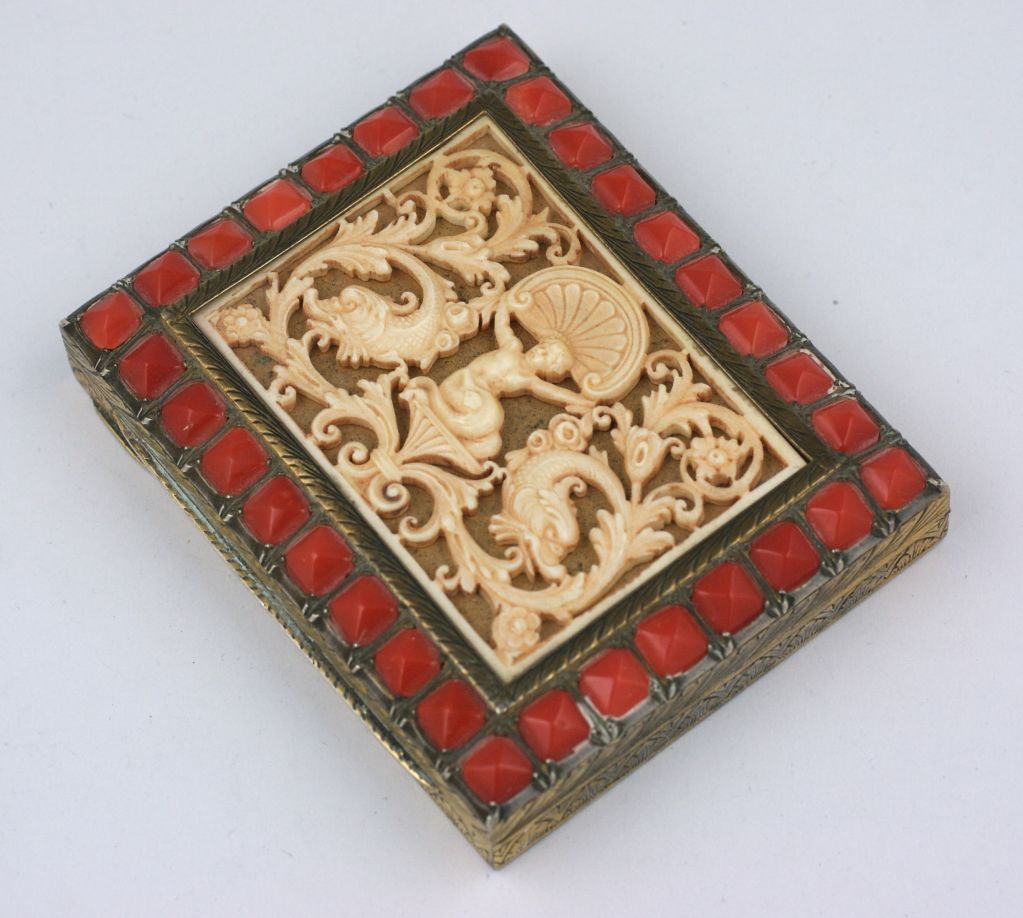 Unusual compact in ivorene and faux carnelian circa 1930. The center motif is molded in a faux ivory celluloid and is surrounded by pointed faux carnelian stones. The box is set in 800 silver (tested) and has elaborately hand etched designs
