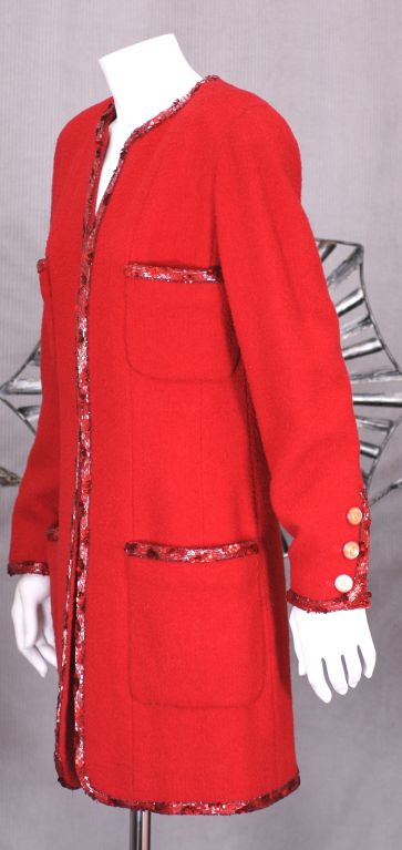 Eine klassische Lagerfeld-Version eines Klassikers aus dem Herbst-Winter 1992-93. Roter Woll-Boucle-Tweed mit einem 3D-Mix aus Bügelperlen und Pailletten in denselben Farbtönen besetzt. Die Jacke wurde verlängert, um multifunktional zu sein, und ist