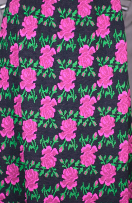 Jupe longue en tricot de laine fabriquée en Italie dans les années 1970. Roses jacquardées dans des tons roses et verts vibrants sur un fond de laine doublement tricotée. Ceinture rayée avec entrée latérale zippée.<br />
Excellent état.<br