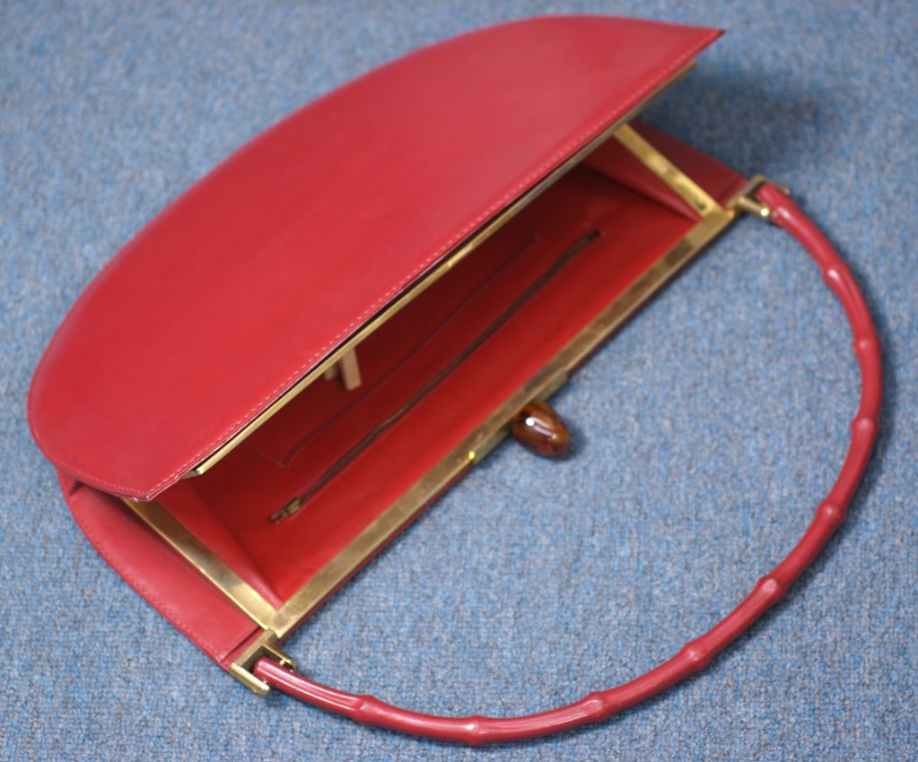 Oversized red calf demilune shaped bag from the 1950s. Retailed by David of Fifth Ave, NY. The bamboo handle is also leather bound. Incredibly chic and collectible bag. Gilt metal mounts and acorn shaped bakelite tortoise clasp. Thin envelope