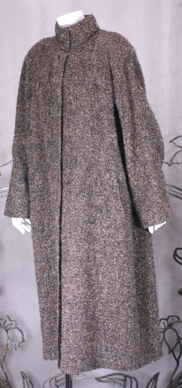 Cappotto in lana bouclé con taglio pieno di Geoffrey Beene. Stile smock con colletto a fascia e carré posteriore arricciato. Insoliti pulsanti con motivo a 