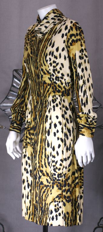 Austere and elegant cowl neck dress with gathered waist and semifull skirt in interesting animal print. Gathered sleeve with button cuffs. Soft rayon broadcloth. Back zip entry. <br />
Excellent condition<br />
39" long<br />
15" from