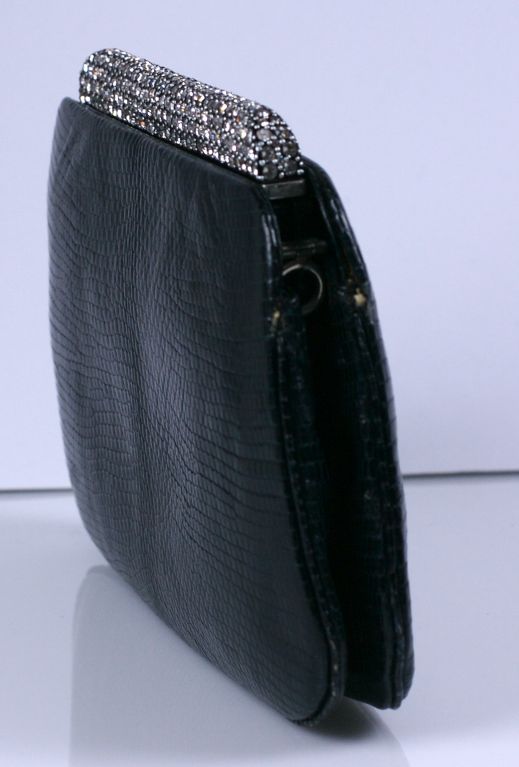 Attractive black snake clutch by Judith Leiber with long pave rhinestone clasp. One center compartment with 2 side compartments. Fittings for shoulder chain. Shoulder chain deficient.<br />
Excellent condition<br />
6.5" x 3" x 3.5"h