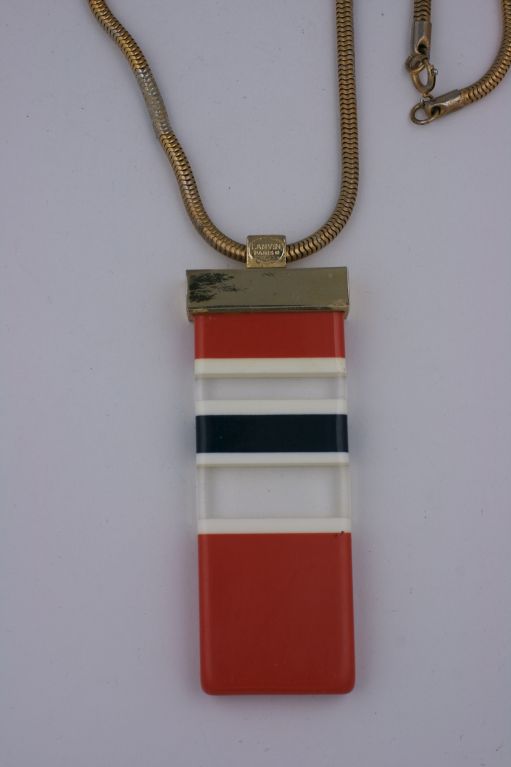 Grande ciondolo di Lanvin degli anni '70 a strisce di resina arancione, bianca, nera e trasparente. <br />
Montatura in metallo dorato.<br />
Firmato Lanvin<br />
Ciondolo 4 x 1,5