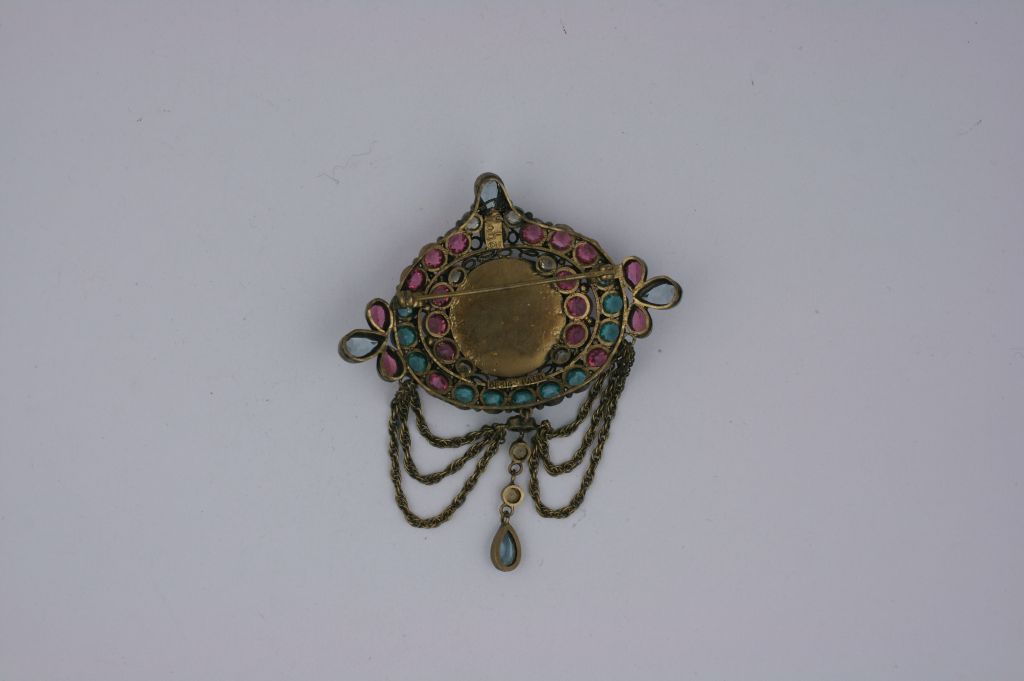 Unusual Hobe brooch from the 1930s. A portrait under glass is set within a jewelled surround of aqua, pink and crystal stones with swagged chain and teardrops. Antique gold settings.<br />
Hand set stones. <br />
Signed 