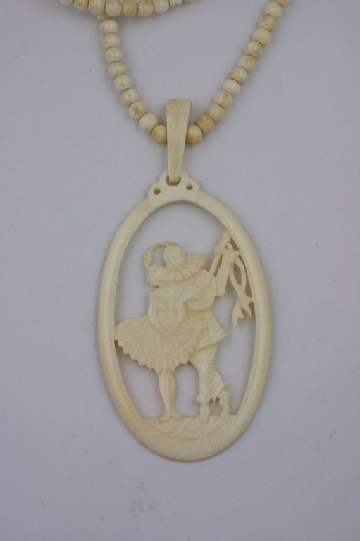 Wonderful carved ivory pendant of a deco Pierrot serenading his lady friend in a oval frame. The beads are approx 5 mm and are approx. 56
