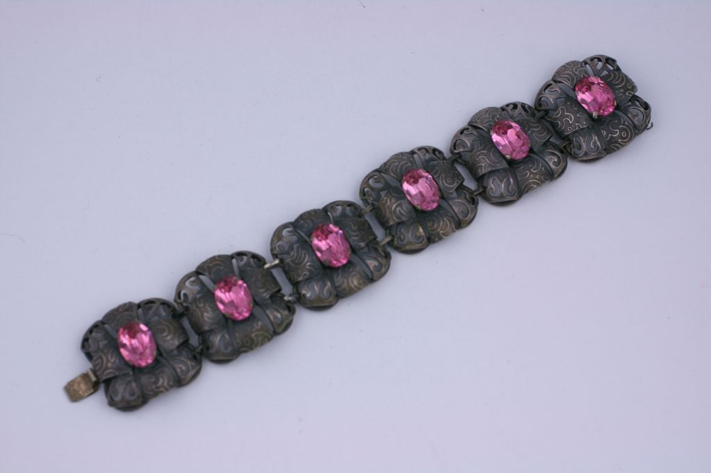 Ungewöhnliches Gliederarmband aus der Zeit um die Wende zum 20. Dimensionale Glieder aus patiniertem, versilbertem und geätztem Metall mit rosa Kristallsteinen auf der Rückseite. Auffälliger Farbkontrast.<br />
Ausgezeichneter Zustand. Frankreich