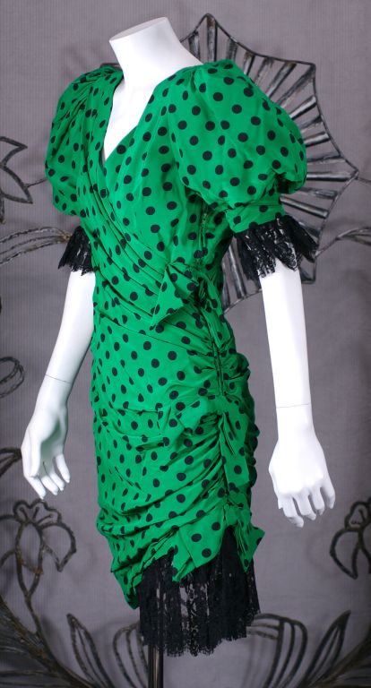 Draped kelly green silk crepe polka dot cocktail dress with lace accents by Isabelle Allard, Paris from the 1980's. The torso is pulled to a cinched side drape zipper with 3 attached bows and pouf sleeves with deep black lace trim. Small Size, 0-2.