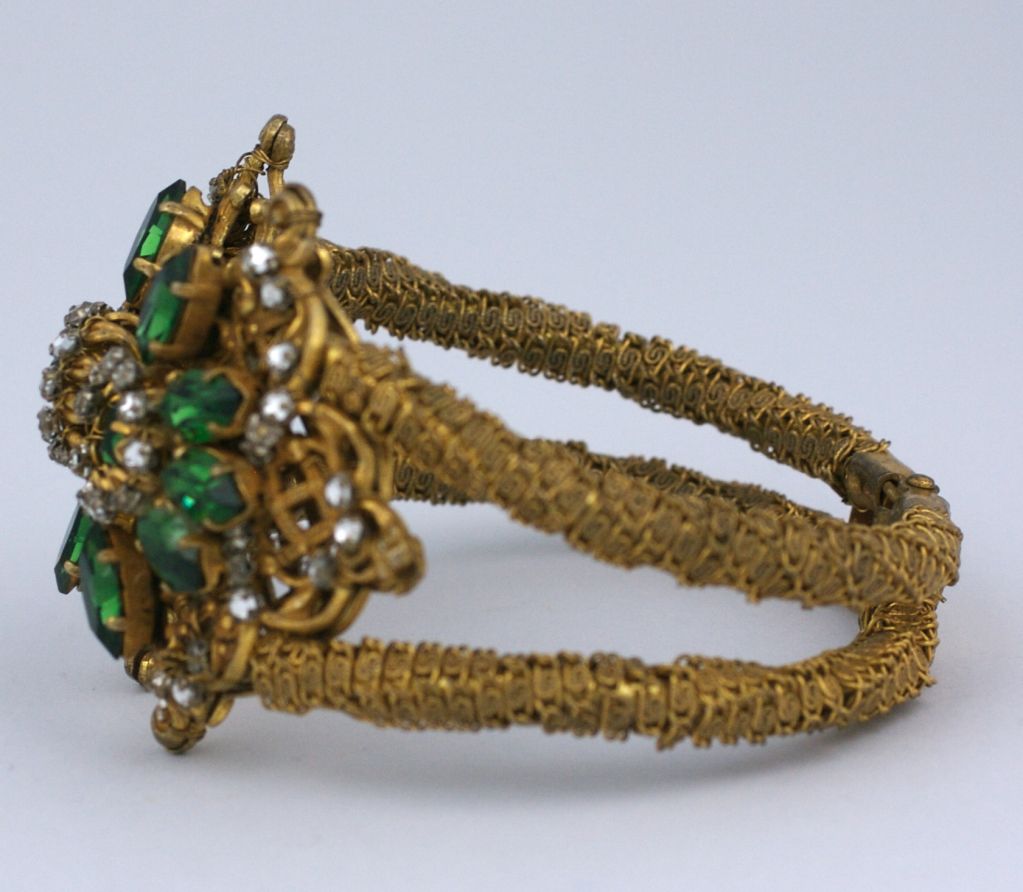 Miriam Haskell hinged clamper bracelet of finely wrapped gilt metal chain, the center motif decorated with round and marquise olivine swarovski stones and crystal rose montes.<br />
Excellent condition<br />
<br />
Interior measure 6.25