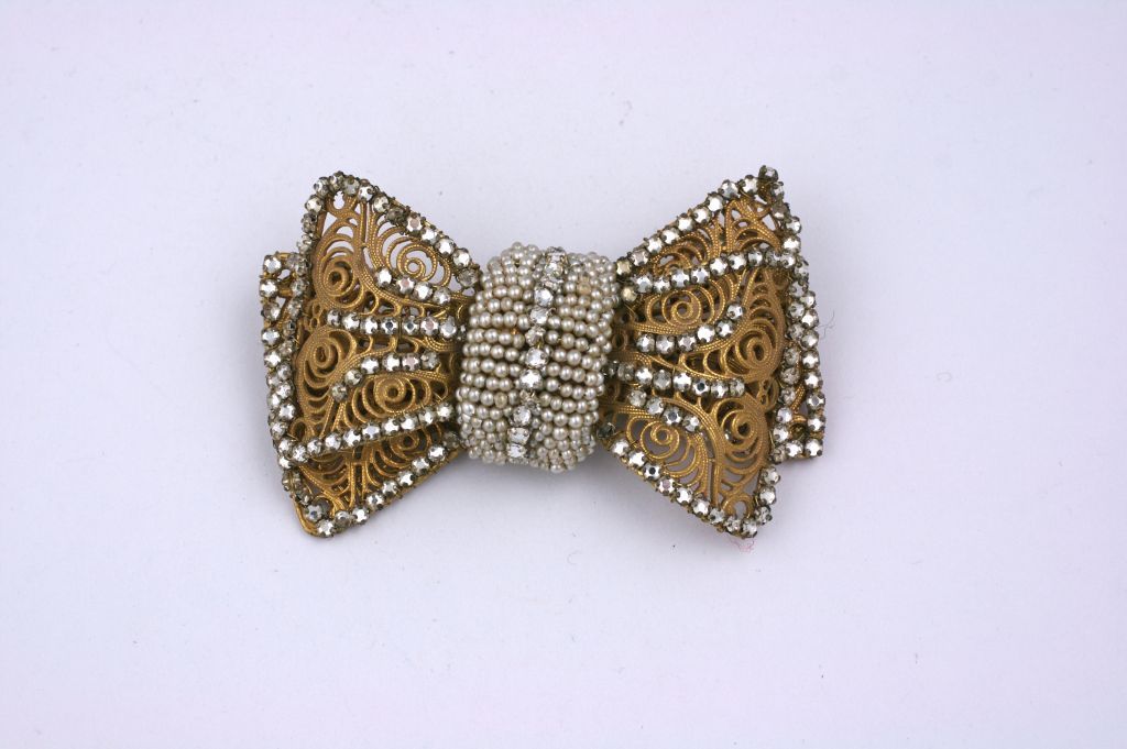 Oversized gilt filigree bow by Miriam Haskell. There are seed pearls embroidered  over the knot with pave rose montees sewn along all the edges. Striking, dimensional and large in scale.<br />
3.25 x 2