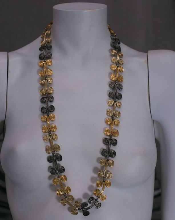 Come designer ospite di Trifari negli anni '70, Diane Love ha esplorato il suo amore per le culture classiche e antiche. 2 toni di oro e argento antico sono combinati per formare questa straordinaria collana. Chiusura a fibbia singola.<br />
A Link