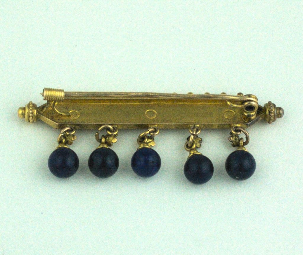 Etruscan revival brooch in 14K gold with lapis ball drops. Revivalist jewelers from the mid to late 19th Century looked to ancient models and techniques to replicate in the modern Victorian era. Intricate florets top the lapis balls. 
Beautifully