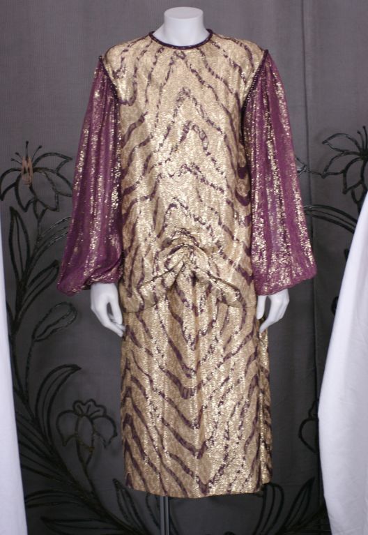 Bill Blass 2 piece lame dress with full,sheer chiffon lame sleeves.<br />
The body and skirt are of burgundy and gold tiger patterned silk lame with twisted cord trim on the neck and armholes. Top is gently gathered at center front hip for drape.