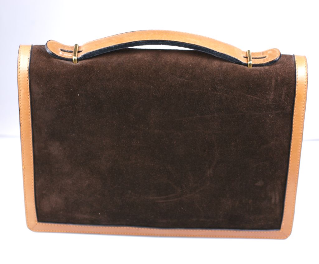 Elegant Clutch with detachable shoulder strap. Deep brown suede edged in natural leather with expanding bellows on side.<br />
Circa 1970s.Gilt stirrup closure.<br />
Excellent condition