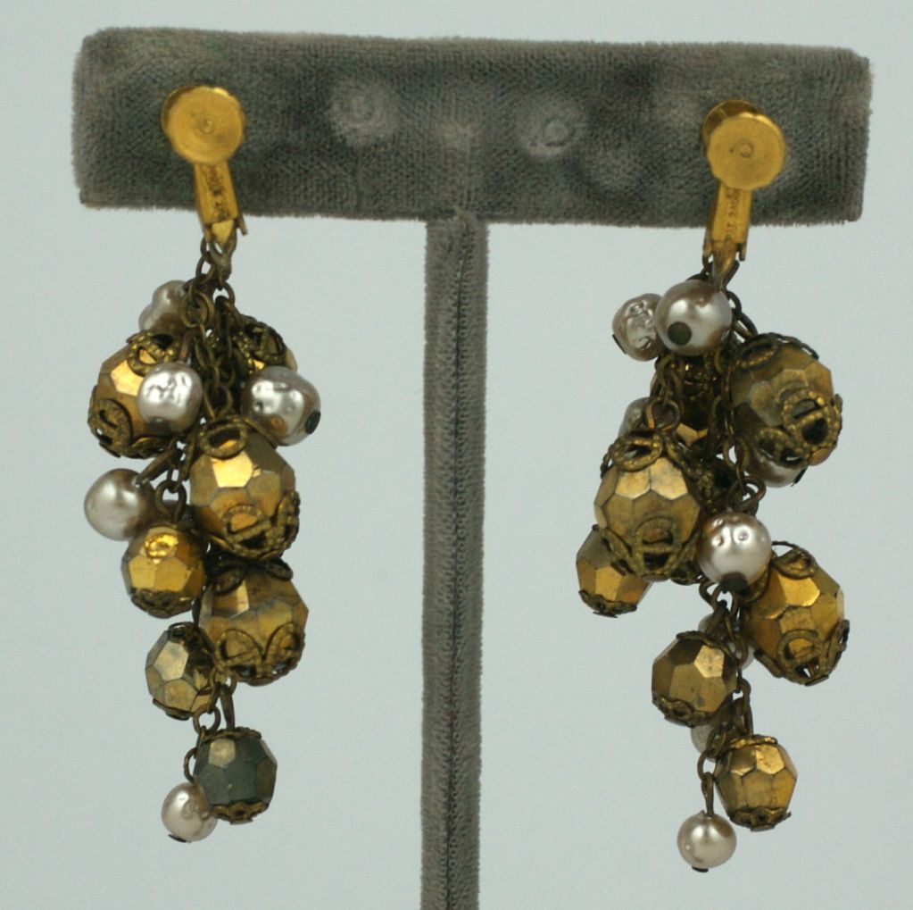 Golden grape cluster earrings by Miriam Haskell circa 1950s. Gold faceted beads and faux pearls in a graduating pattern. Adjustable clip back fittings, Russian gold Miriam Haskell finish.<br />
Excellent condition