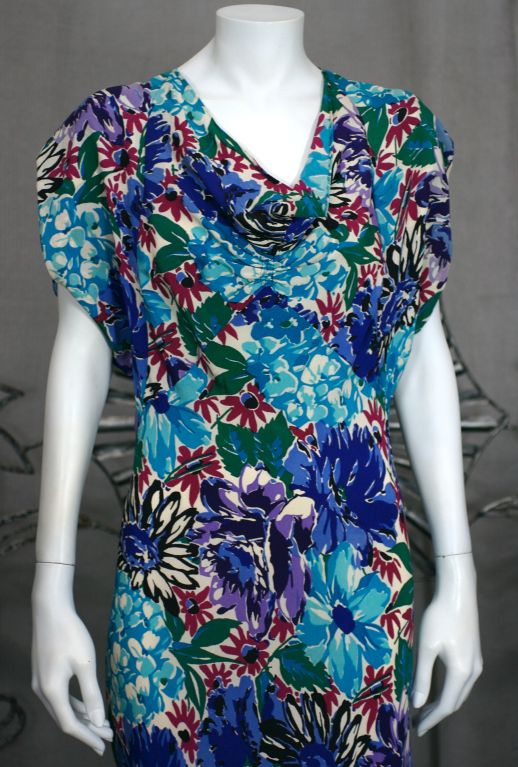 Unusual and timeless floral crepe silk gown from the 1930s with cowled, draped neckline, capped sleeves and wonderful looped draped back detail. Luscious blue/purple flower print and full bias cut skirt. Fitted through the hips to release into large