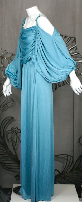 Draped blue jersey gown from Paraphernalia with long ties that ruch the draped bodice and form ties at the shoulder. Cut off the shoulder with huge kimono sleeves that are gathered at wrist. Designers such as Betsey Johnson and Michael Mott worked