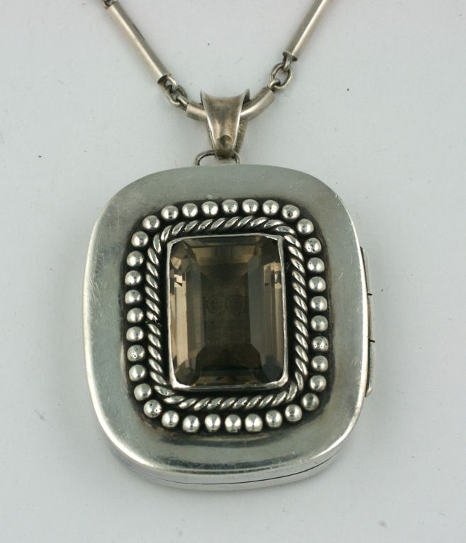 Oversized locket with huge smokey topaz center stone by Antonio Pineda. Made in Mexico in the Art Deco period, the twisted banding and silver shot work are reminiscent of Despres' work in France. Heavy gauge sterling with hand forged chain makes