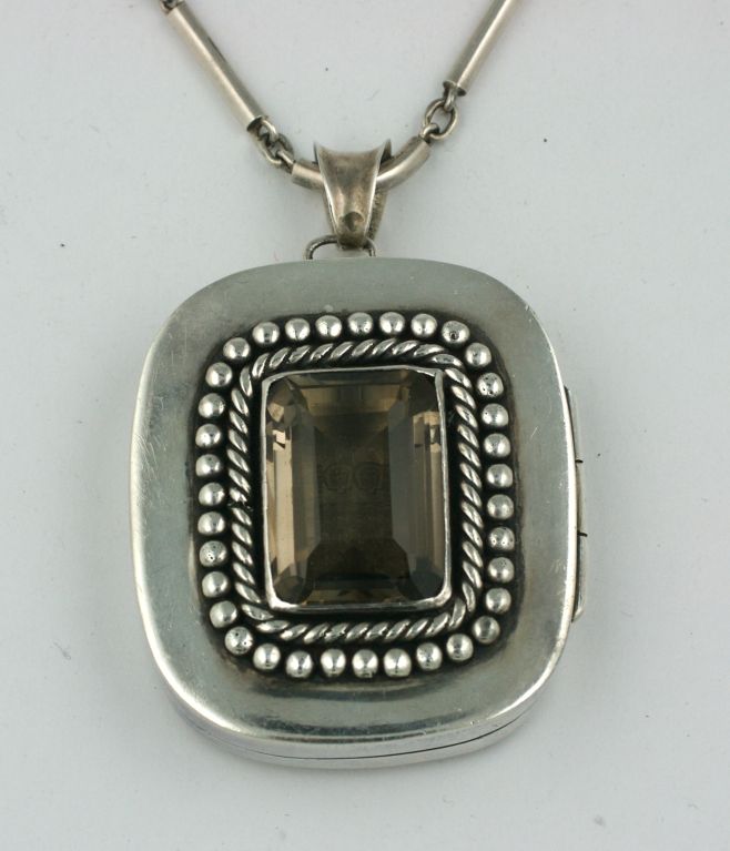 Medaglione oversize con enorme pietra centrale di topazio fumé di Antonio Pineda. Realizzata in Messico nel periodo Art Deco, la lavorazione a bande ritorte e i pallini d'argento ricordano il lavoro di Despres in Francia. Il calibro pesante in