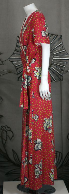 Charming wrap dress from the 1930s in graphic floral crisp cotton seersucker with lace trim. Red with lime dots and morning glories.<br />
Excellent condition. Adjustable waist with self ties. <br />
<br />
Length: 56