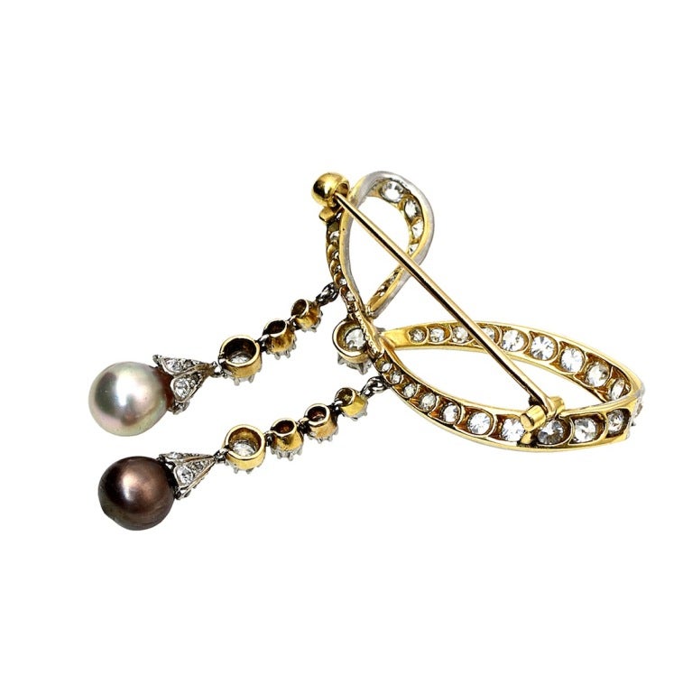An Belle Epoque Tiffany & Co. brooch with two natural saltwater pearls with a looped diamond-set bow centering one old European-cut diamond approximately 0.40 ct., suspending two lines of 7 prong-set diamonds, tipped by one pinkish-brown pearl