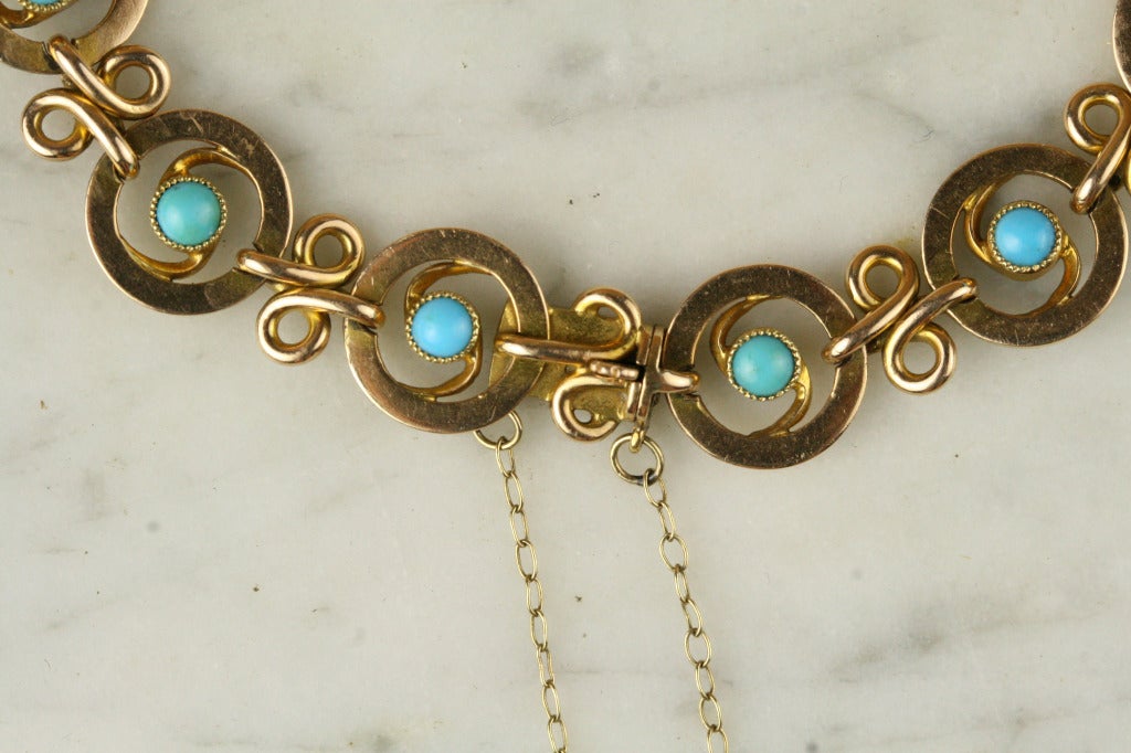 - 15k yellow gold, 12 3mm Persian turquoise cabochons
- Made in England

A wonderful mix of Art Nouveau and Egyptian Revival styles, this antique gold bracelet features bezel-set turquoise stones at the abstract daisy-like links. With a cleverly